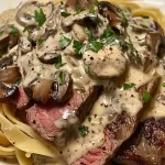 A bowl of steak pasta with creamy mushroom sauce topped with fresh parsley.