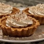 Finished Pumpkin Tarts with Toppings: Finished pumpkin tarts topped with whipped cream and cinnamon.